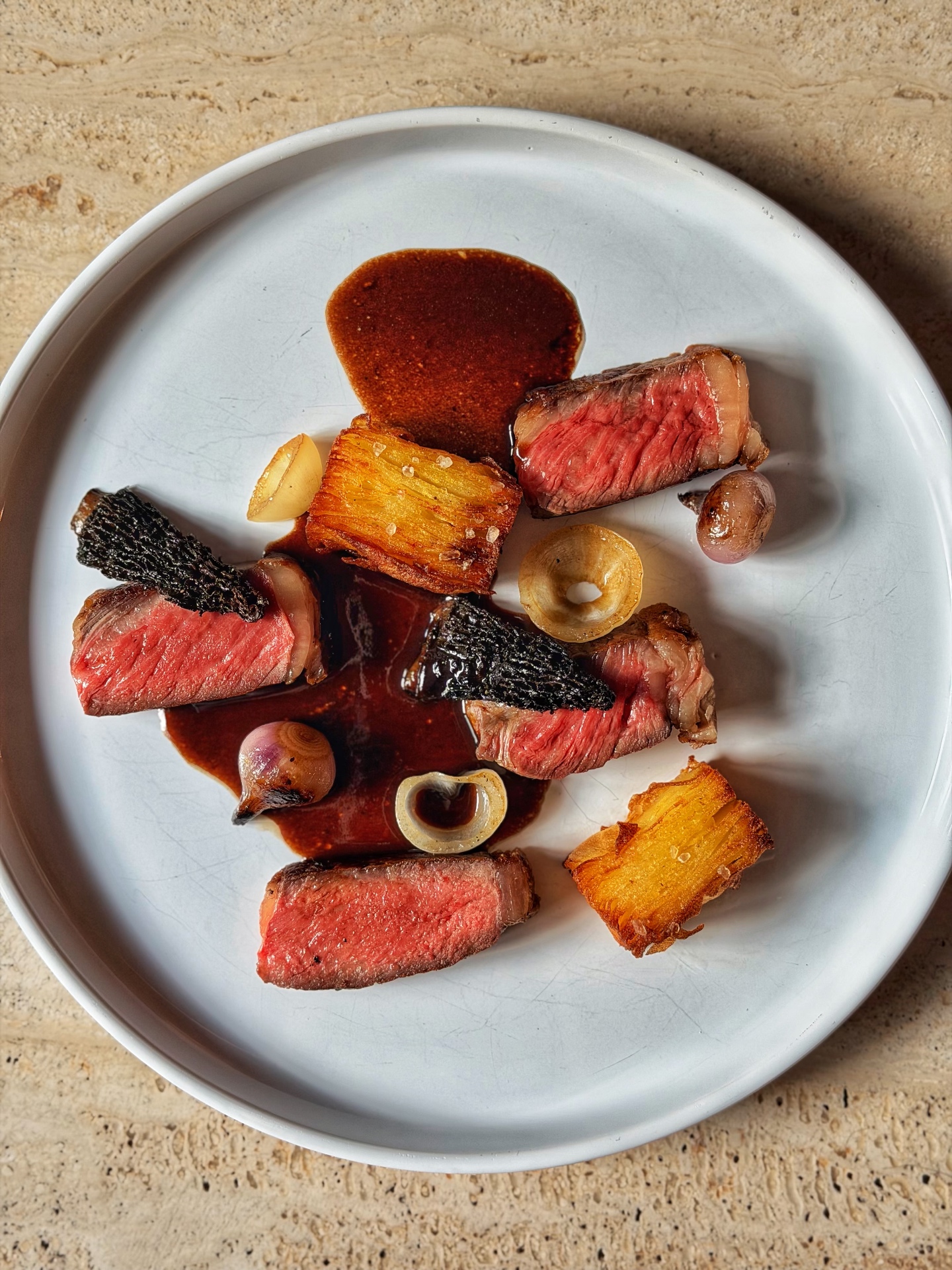Sliced steak with pommes anna, glazed shallots and pan sauce